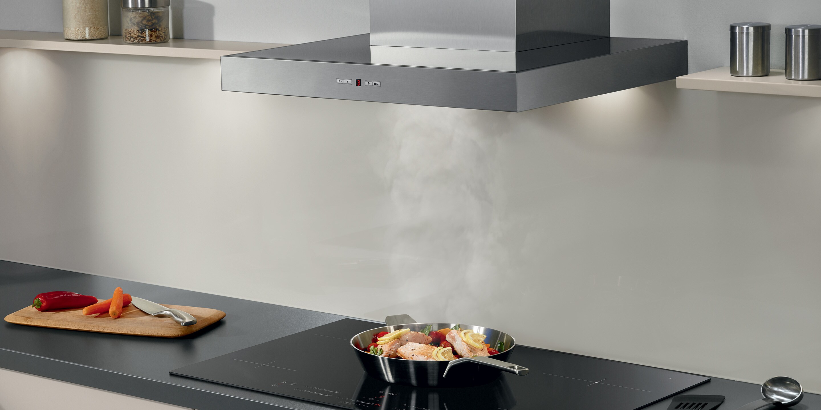 Salmon cooking on an induction hob while the excess steam is being extracted by the cooker hood.