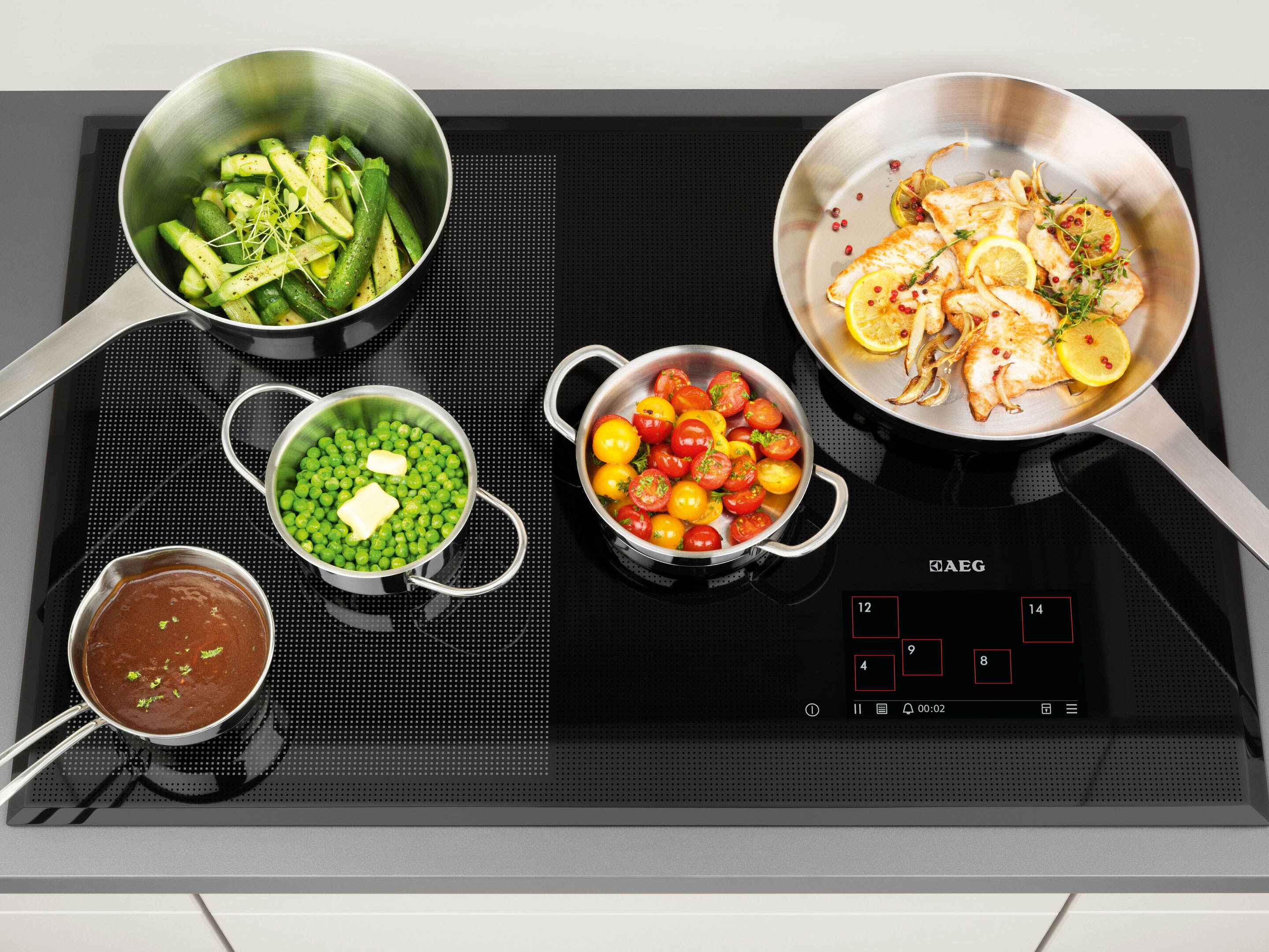A selection of different sized pans all cooking on an AEG induction hob