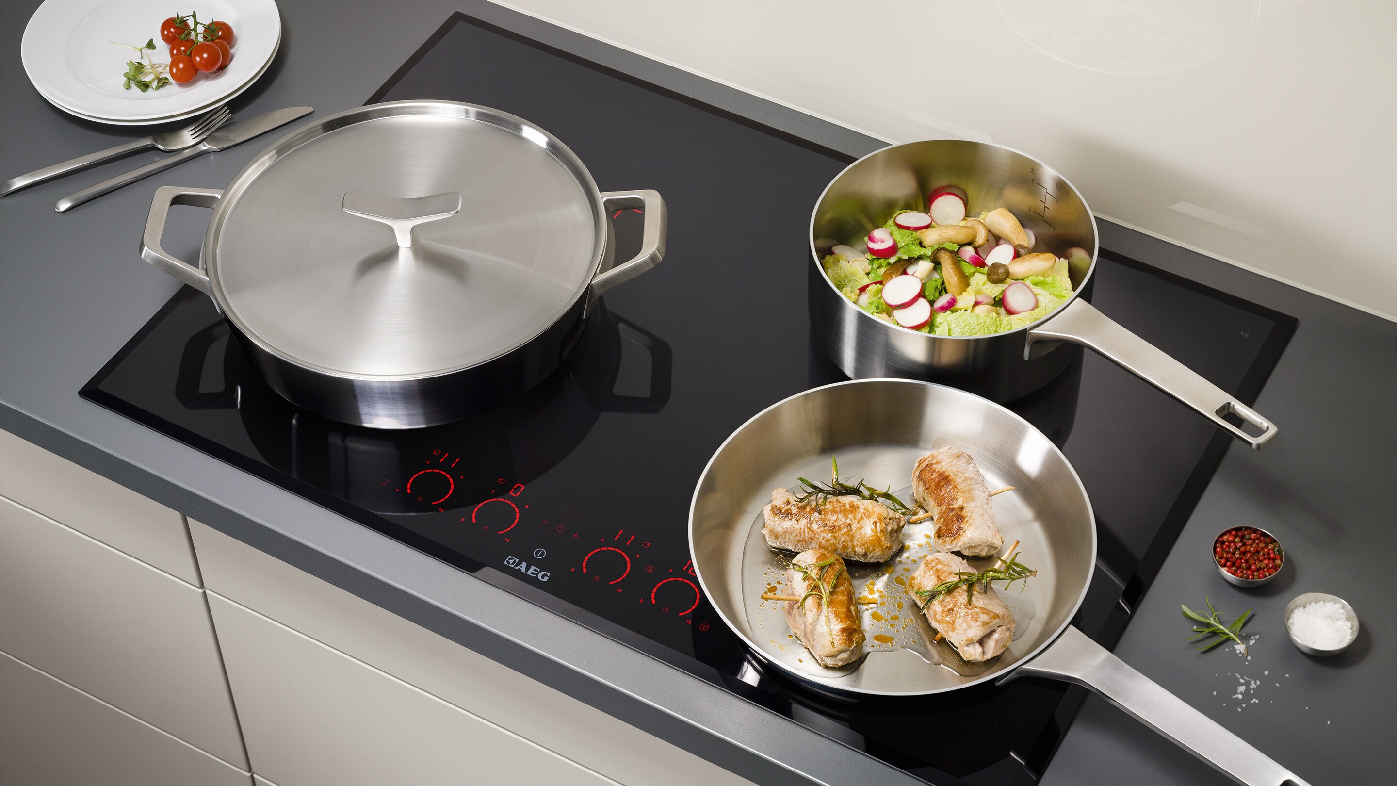 Three different types of pan all cooking safely on an Electrolux induction hob