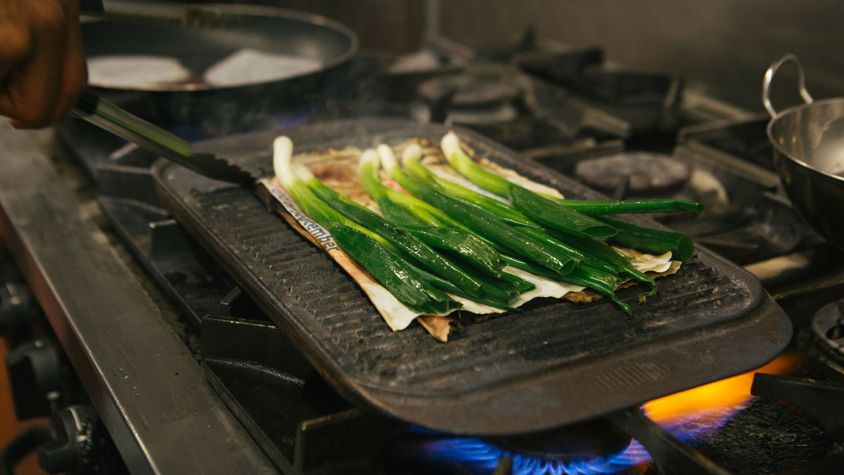 Spring onions frying above a flame