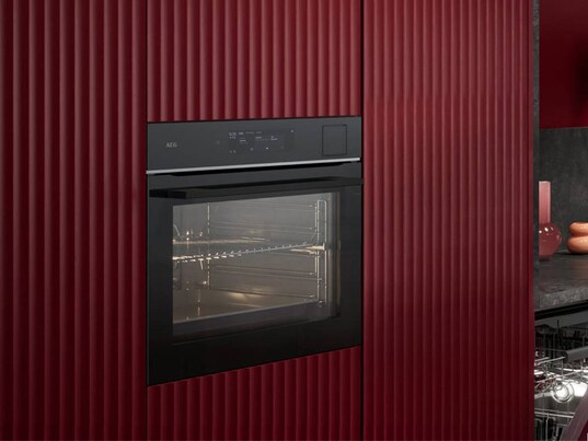 View of an oven surrounded by red paneling.