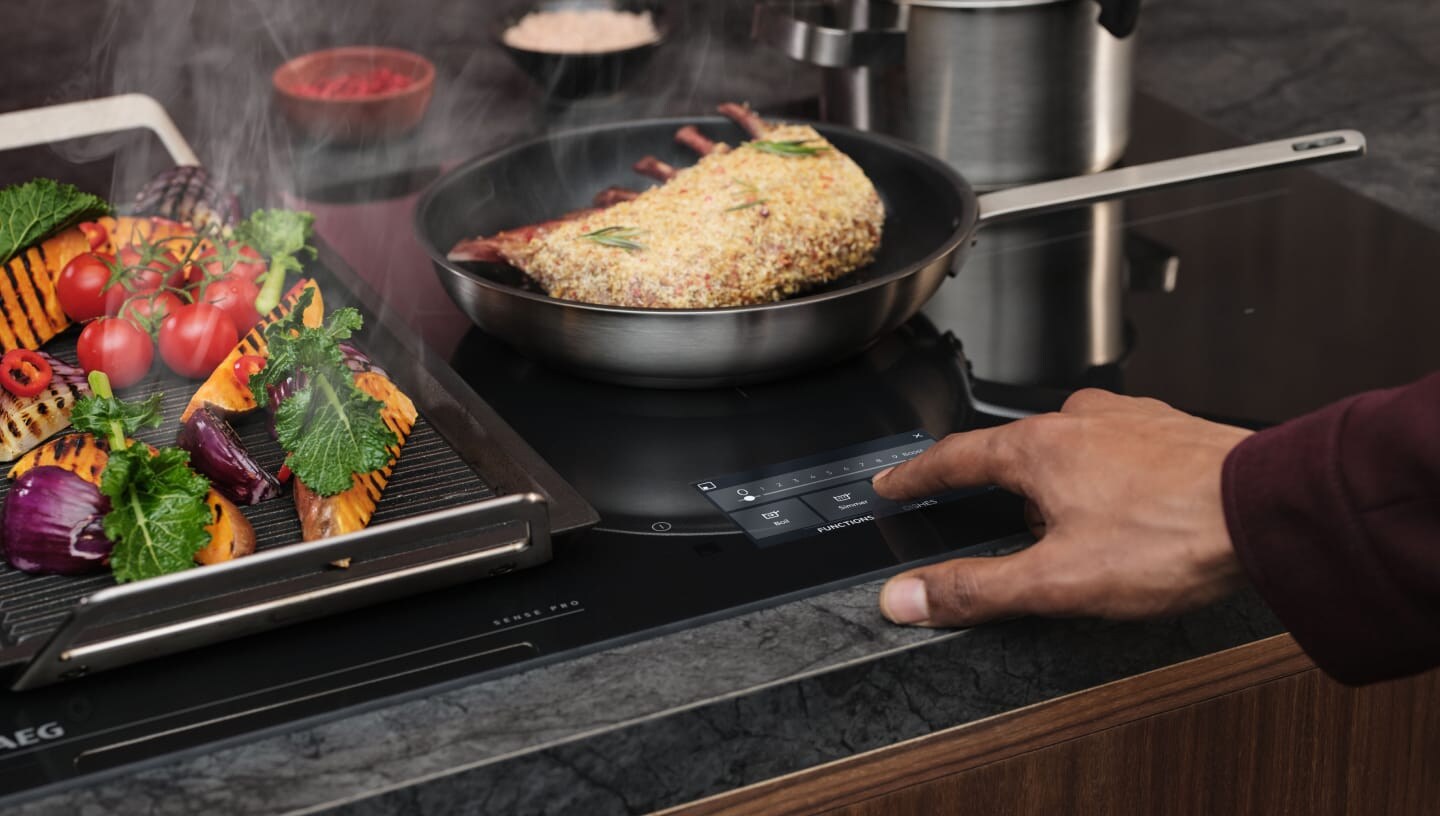 A finger is touching the control panel on an induction hob.