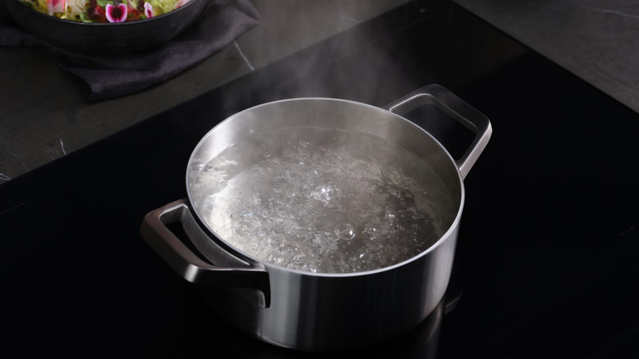 A casserole with boiling water on an induction hob.