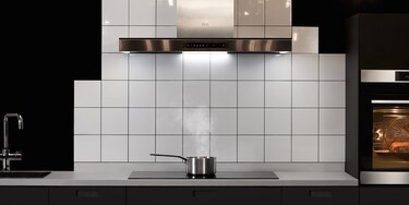 Salmon cooking on an induction hob while the excess steam is being extracted by the cooker hood