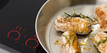 A selection of induction cookware cooking food on an AEG induction hob