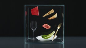 A selection of cutlery, plates and produce in a glass box to represent the experience pillar of Taking Taste Further.