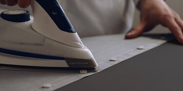 A male ironing his shirt