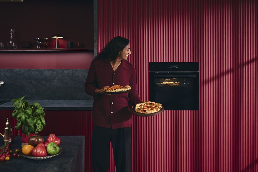 Woman holding Pizza near oven