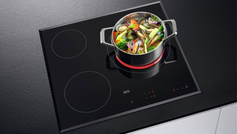Food cooking in a pot placed on an AEG hob.