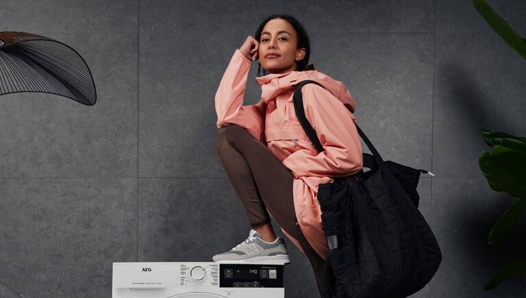 Woman leaning against an AEG washer-dryer.