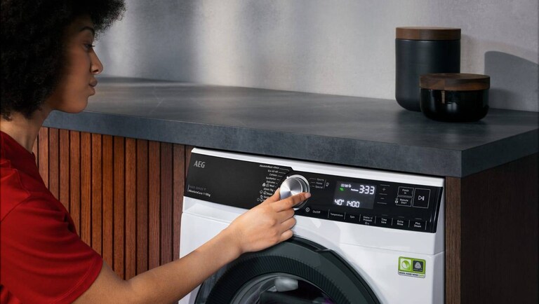 Woman setting up the 30 degrees wash cycle on an AEG washing machine