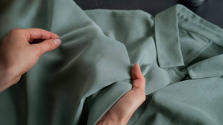 Hands holding a green shirt for inspection.