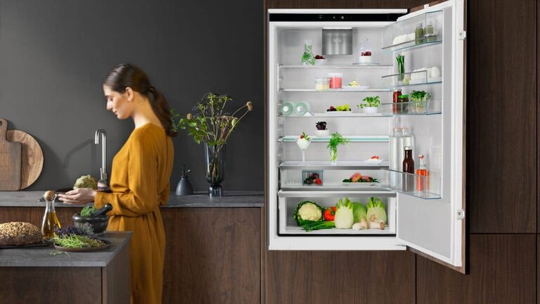 Woman standing in a kitchen with a fridge door open
