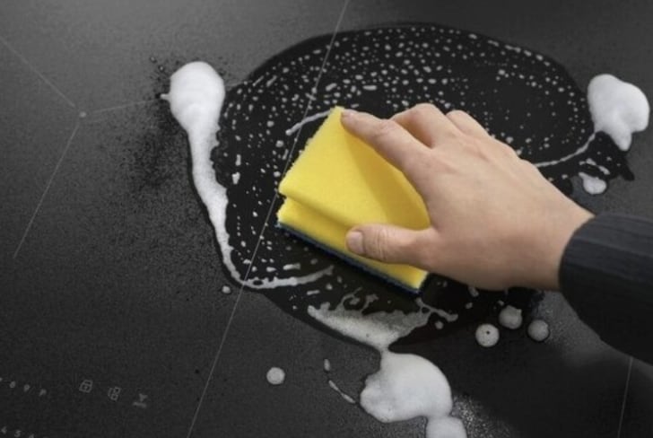 Man cleaning hob with a sponge