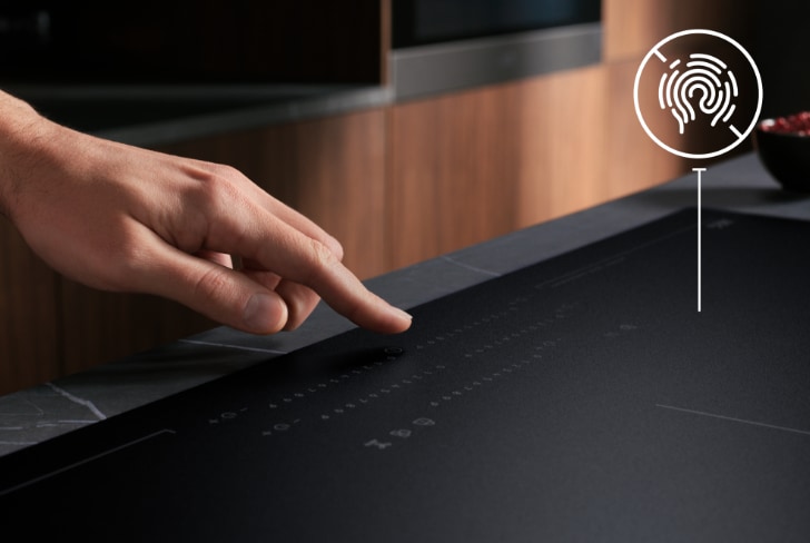 Finger touching a black matt induction hob
